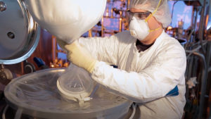 Photo of a lab technician attaching an EZ BioPac bag to a drum during a biopharmaceutical manufacturing process.